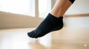 A student in a plank position wearing full-toe coverage grip socks for maximum traction on a studio floor.